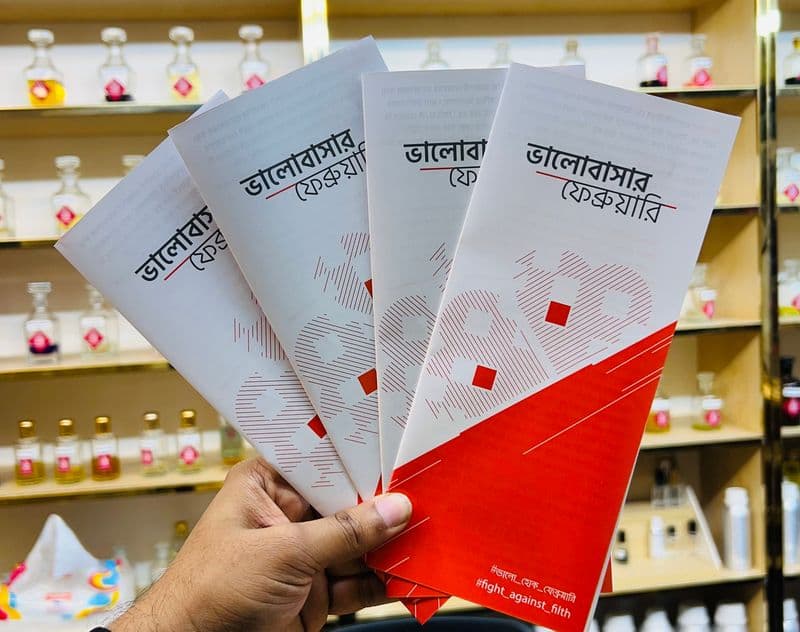 হাতে ধরা কয়েকটি লিফলেট, পেছনে দোকানের তাক