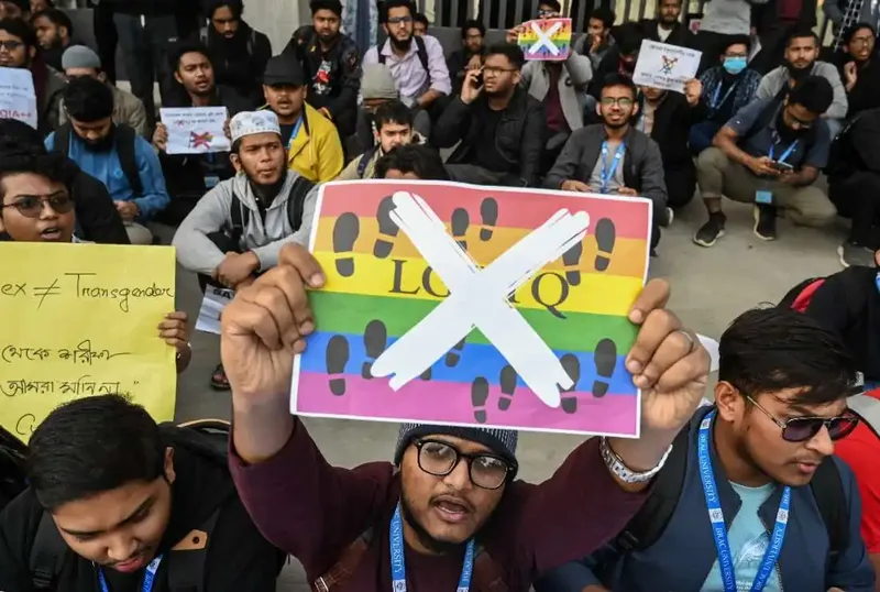 এলজিবিটি পতাকায় ক্রস চিহ্ন দেওয়া প্ল্যাকার্ড হাতে বিক্ষোভরত শিক্ষার্থীরা